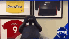 a person is sitting in front of a wall with jerseys on it including one that says lukaku 9