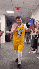 a man in a yellow lakers jersey is dancing in a hallway .