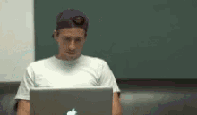 a man wearing a purple hat is using an apple laptop computer