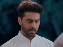 a man with a beard and a white shirt is looking down