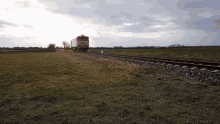 a train is going down the tracks in the middle of a grassy field
