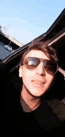 a young man wearing sunglasses is taking a picture of himself in a car .