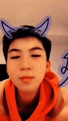 a young man wearing devil horns and an orange sweater