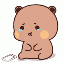 a cartoon teddy bear is crying and sitting next to a cell phone .