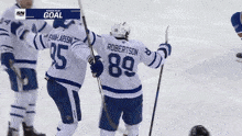 a group of hockey players are celebrating a goal and one of them has the number 23 on his back