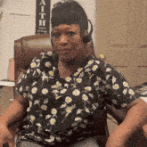 a woman wearing headphones is sitting in a chair in front of a sign that says " faith "