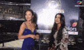 two women are standing in front of a big boss poster