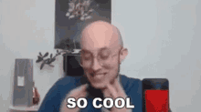 a bald man wearing glasses and a blue shirt is talking into a microphone .
