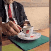 a man in a suit and tie is sitting at a table with a cup of coffee and a saucer