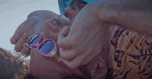 a man wearing pink sunglasses is being held by another person