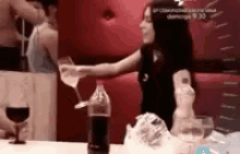 a woman is pouring a drink into a glass