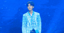 a young man in a blue plaid jacket is standing on a stage .