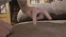 a person 's hand is laying on a couch with their index finger pointing up