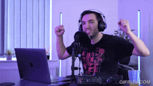 a man wearing headphones is sitting in front of a laptop and a microphone with a gifrun.com watermark