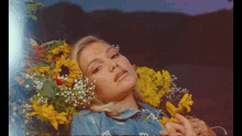 a woman in a blue shirt is laying on a bed with flowers on her head