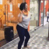 a woman in a white tank top and black jeans is dancing on a sidewalk