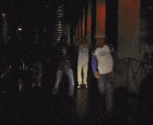 a man wearing a hat and a shirt that says ' r.i.p. ' on it is dancing in the dark