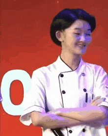 a woman in a chef 's uniform is standing with her arms crossed .