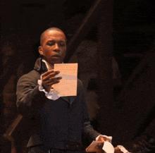 a man in a suit is holding a piece of paper in his hands