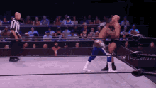 two wrestlers in a wrestling ring with a referee watching