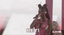 a woman is singing into a microphone while wearing a pink top .
