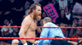a man in a blue shirt stands in a wrestling ring with a sign that says meet