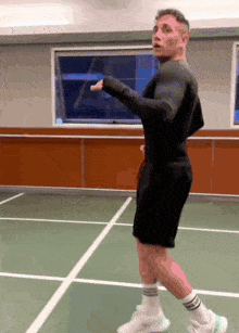 a man in a black shirt and black shorts stands on a tennis court