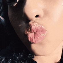 a close up of a woman blowing a kiss with a black background