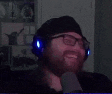 a man wearing glasses and headphones is smiling in a dark room