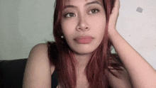 a woman with red hair looks at the camera with her hand on her head