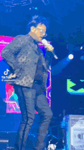 a man is singing into a microphone on a stage with a tiktok watermark