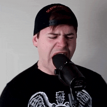 a man singing into a shure microphone while wearing a black hat