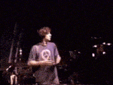 a man in a purple shirt is dancing on a stage in a dark room .