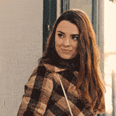 a woman with long hair wearing a plaid jacket is smiling