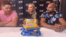 a group of people sitting in front of a wall with aew written on it