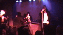 a man singing into a microphone on stage in front of a crowd