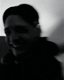 a man in a black jacket is smiling in a black and white photo