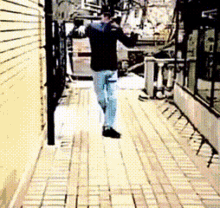 a man in a black jacket is walking down a sidewalk with a bicycle in the background