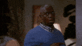 a man wearing a blue sweater and plaid shirt is looking at something