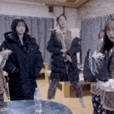 a group of women are standing around a table with a bottle of water
