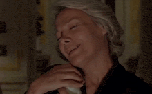 a woman with gray hair is laughing with her hand on her mouth