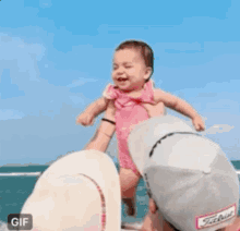 a little girl in a pink dress is sticking her tongue out while sitting on the floor .