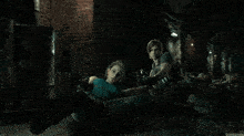 a man and a woman are laying on the floor holding guns in a dark room .