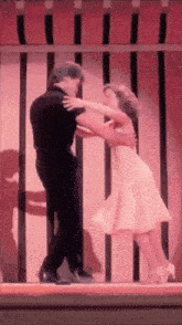 a man and a woman are dancing on a stage in front of a pink awning