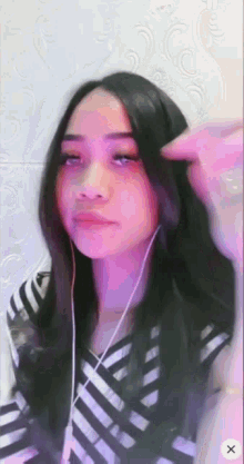 a woman wearing headphones and a striped shirt is looking at the camera with an x in the corner