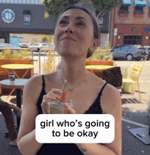 a woman drinking from a cup with a straw and a sign that says girl who 's going to be okay