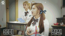 a girl in a school uniform is sitting at a desk with a cup of water