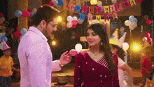 a man and woman are standing next to each other at a birthday party with balloons and a banner that says happy birthday .