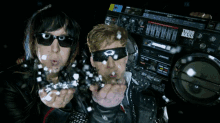 two people blowing confetti in front of a radio that says third bass