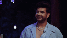 a man with a beard and a pearl necklace smiles for the camera